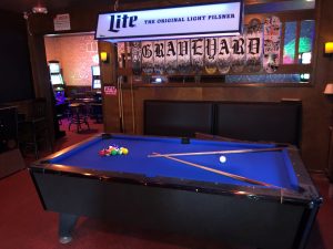 Blue felt coin operated pool table with cues crossing each other on table
