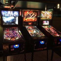 Three pinball machines next to each other with different themes